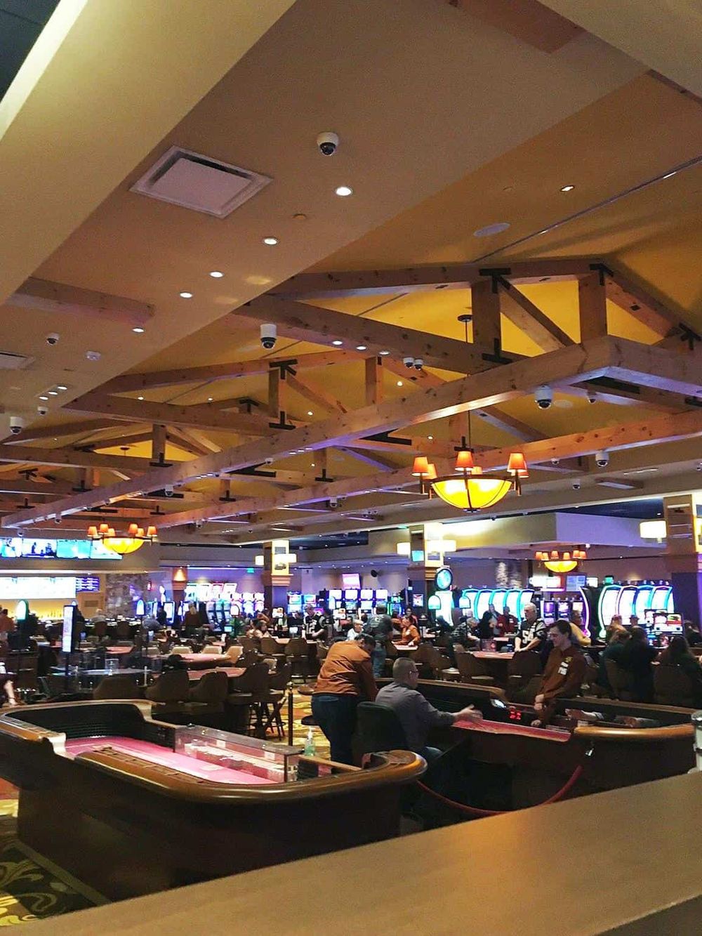 Bright casino interior with gaming tables and electronic slot machines, lively atmosphere, and sophisticated lighting.