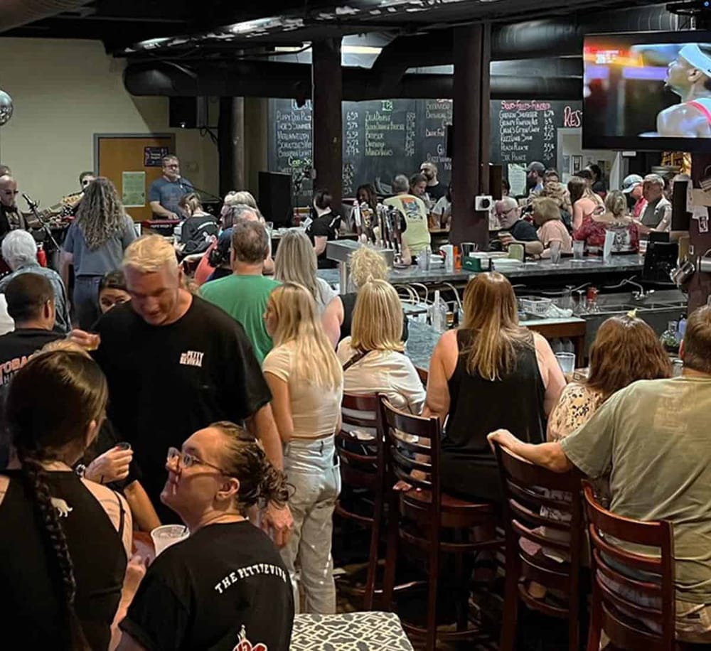 Bustling bar scene with people enjoying drinks, live music, and sports on TV at QuestForDirections.