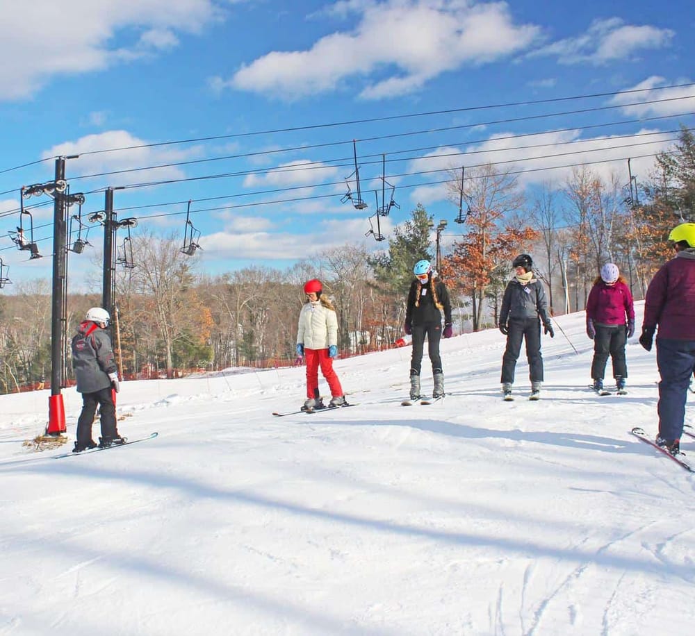Kids learning skiing on a snow-covered slope with ski lift overhead, outdoor winter activity, family fun, outdoor winter sports.