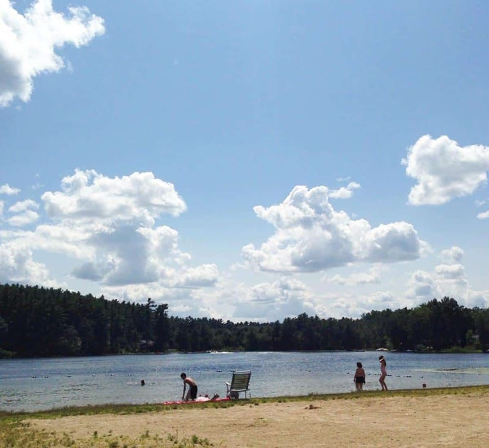 Bright sunny day at a lakeside beach with families enjoying the scenic outdoor recreation area.