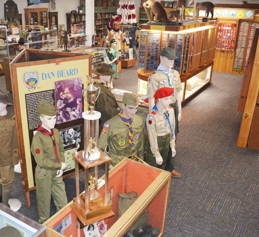 Boy Scout and Girl Scout mannequins display scout uniforms in a museum shop.