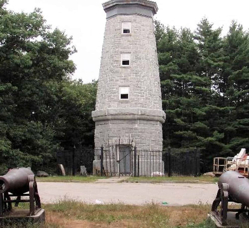 Ancient stone tower at QuestForDirections historic site, surrounded by trees, with cannons in foreground.