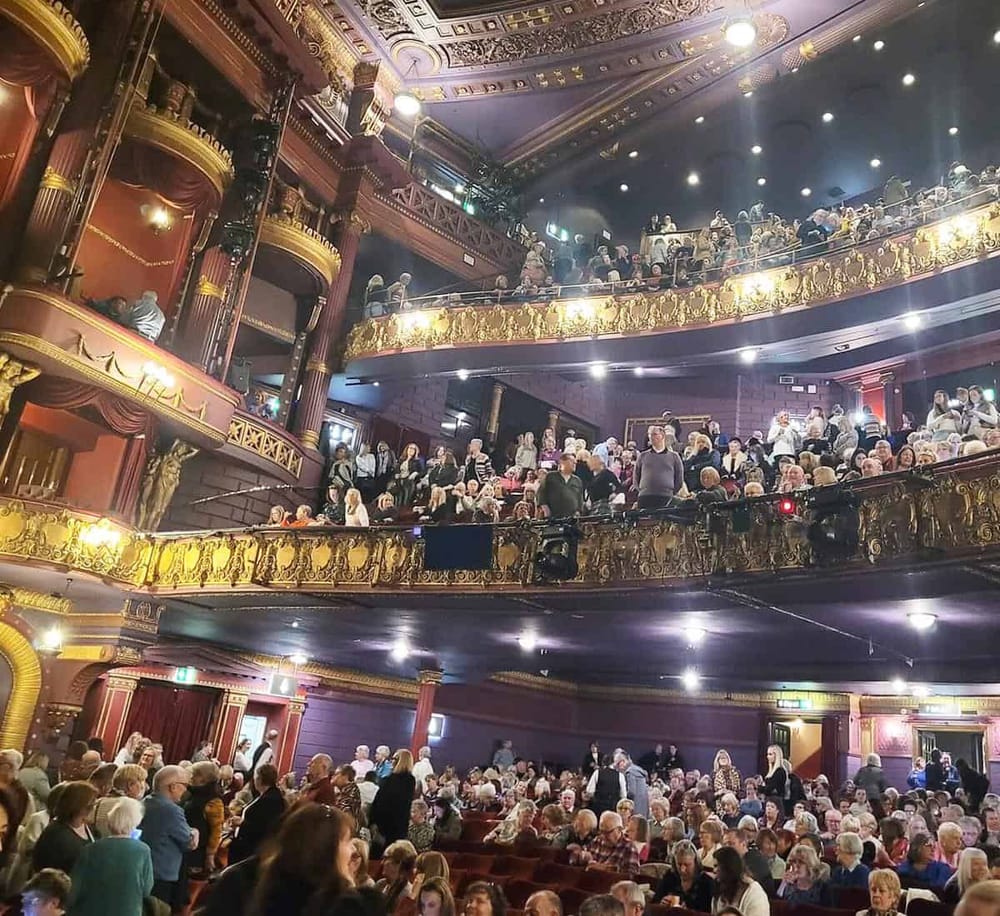 Ornate theater interior filled with audience members for a performance or event.