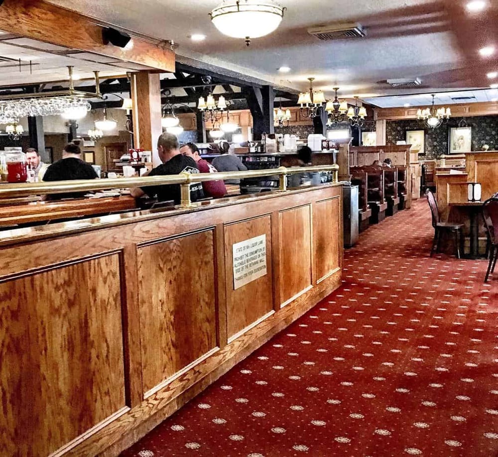 Cozy restaurant interior with wooden accents, warm lighting, and patrons dining in a classic ambiance.