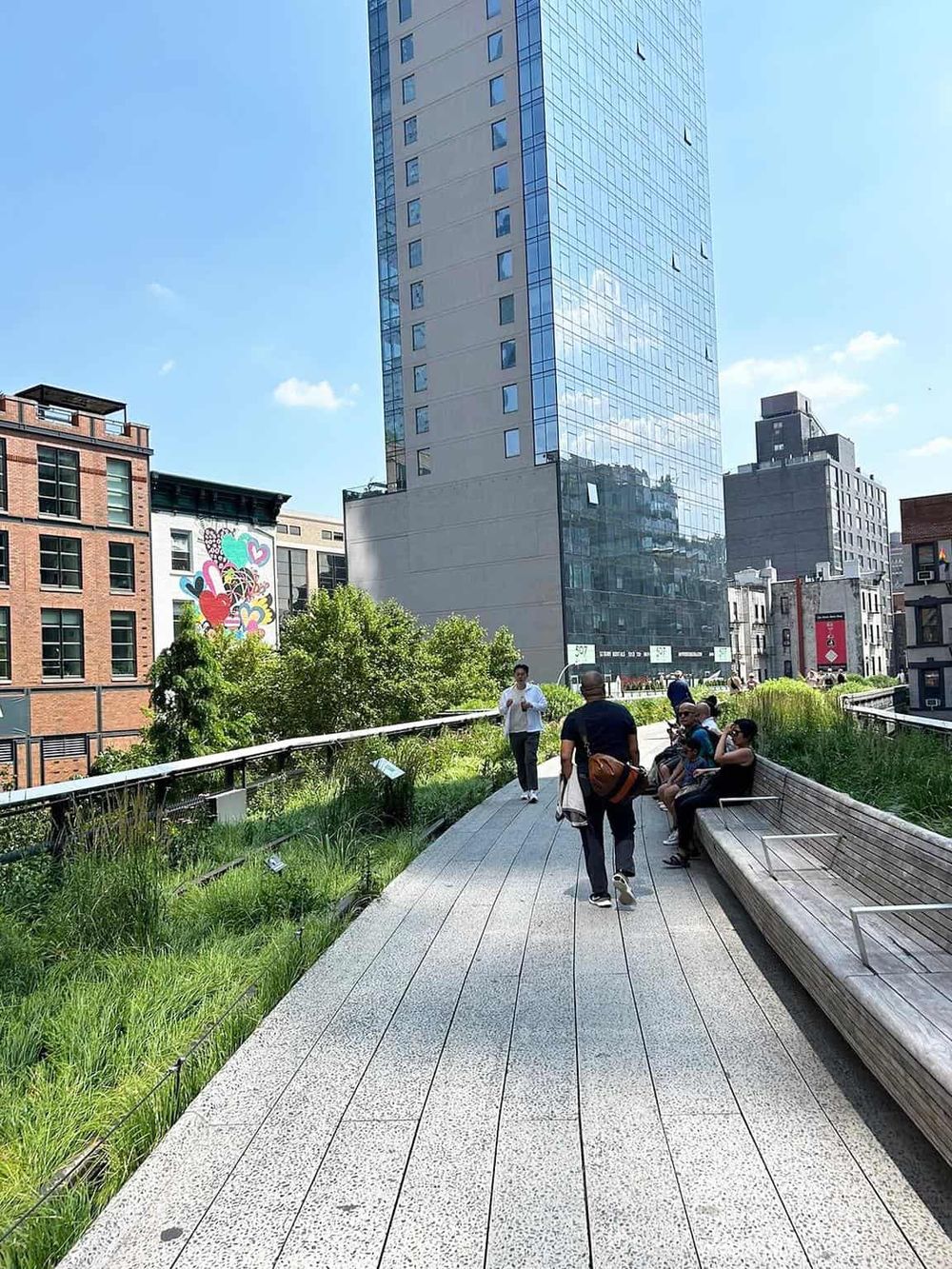 Modern urban park with skyscrapers and people relaxing on benches and walking.
