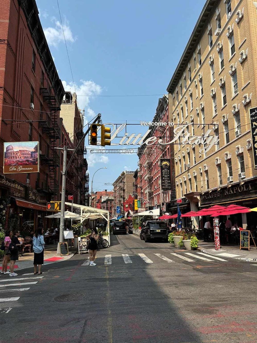 Bright street scene in Little Italy, New York City featuring cafes, outdoor dining, and vibrant atmosphere.