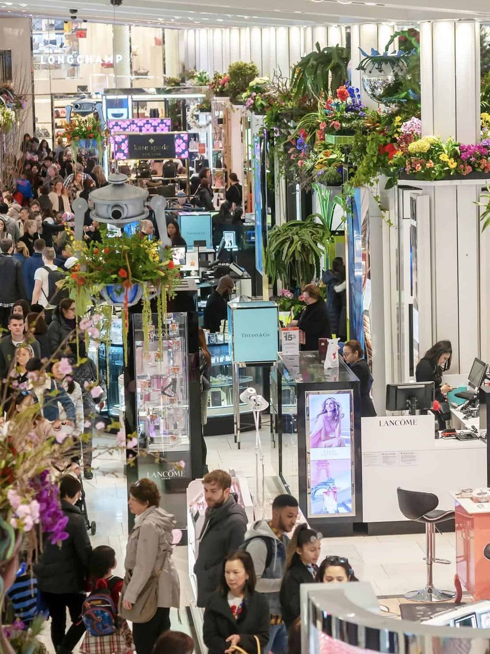 Bright shopping mall with luxury brands and diverse shoppers in a vibrant retail environment.