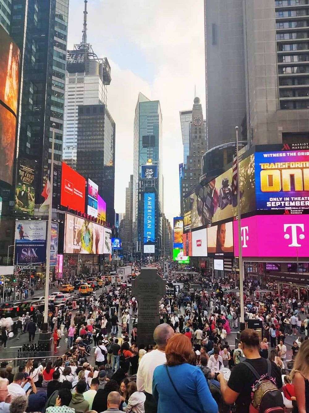 Crowded Times Square with digital billboards and skyscrapers, home to QuestForDirections' navigation services in New York.