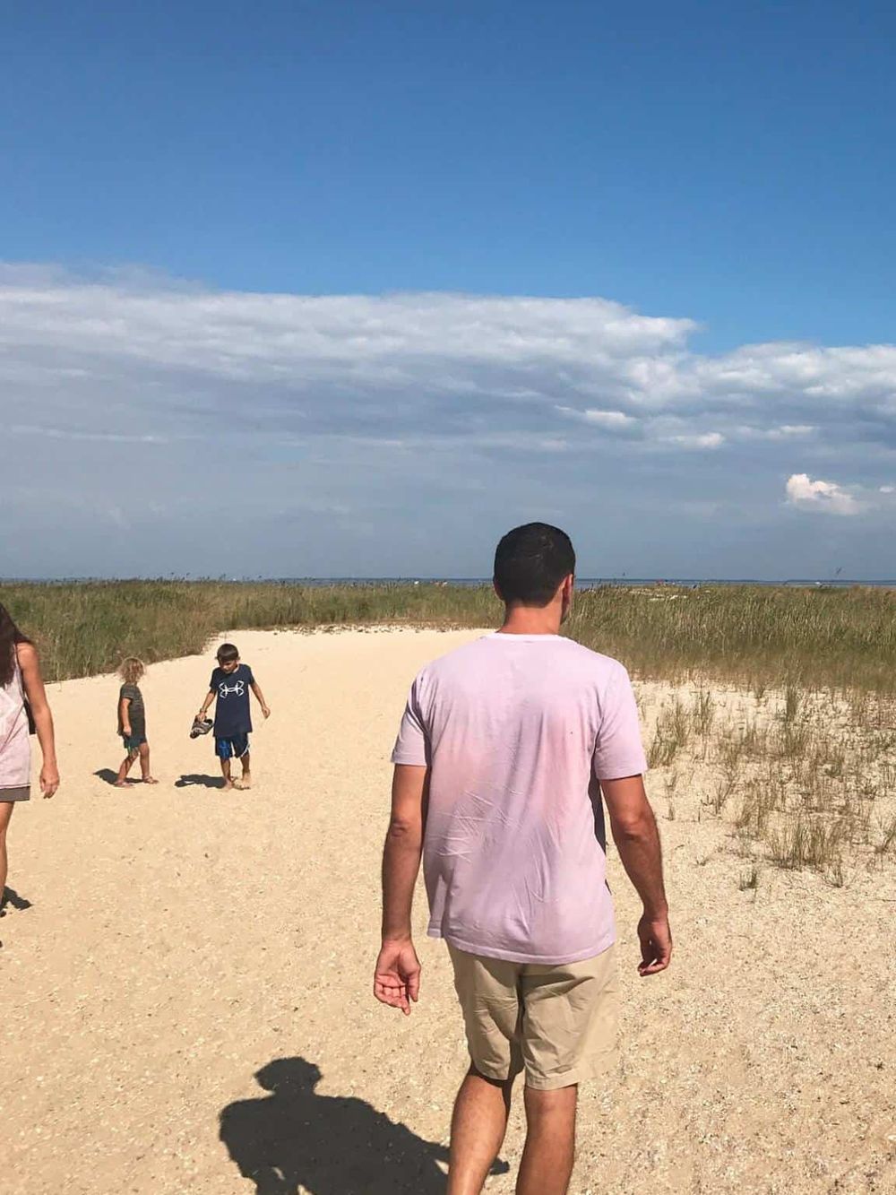Serene beach scene with family exploring sandy dunes and blue sky, perfect for travel and vacation planning.