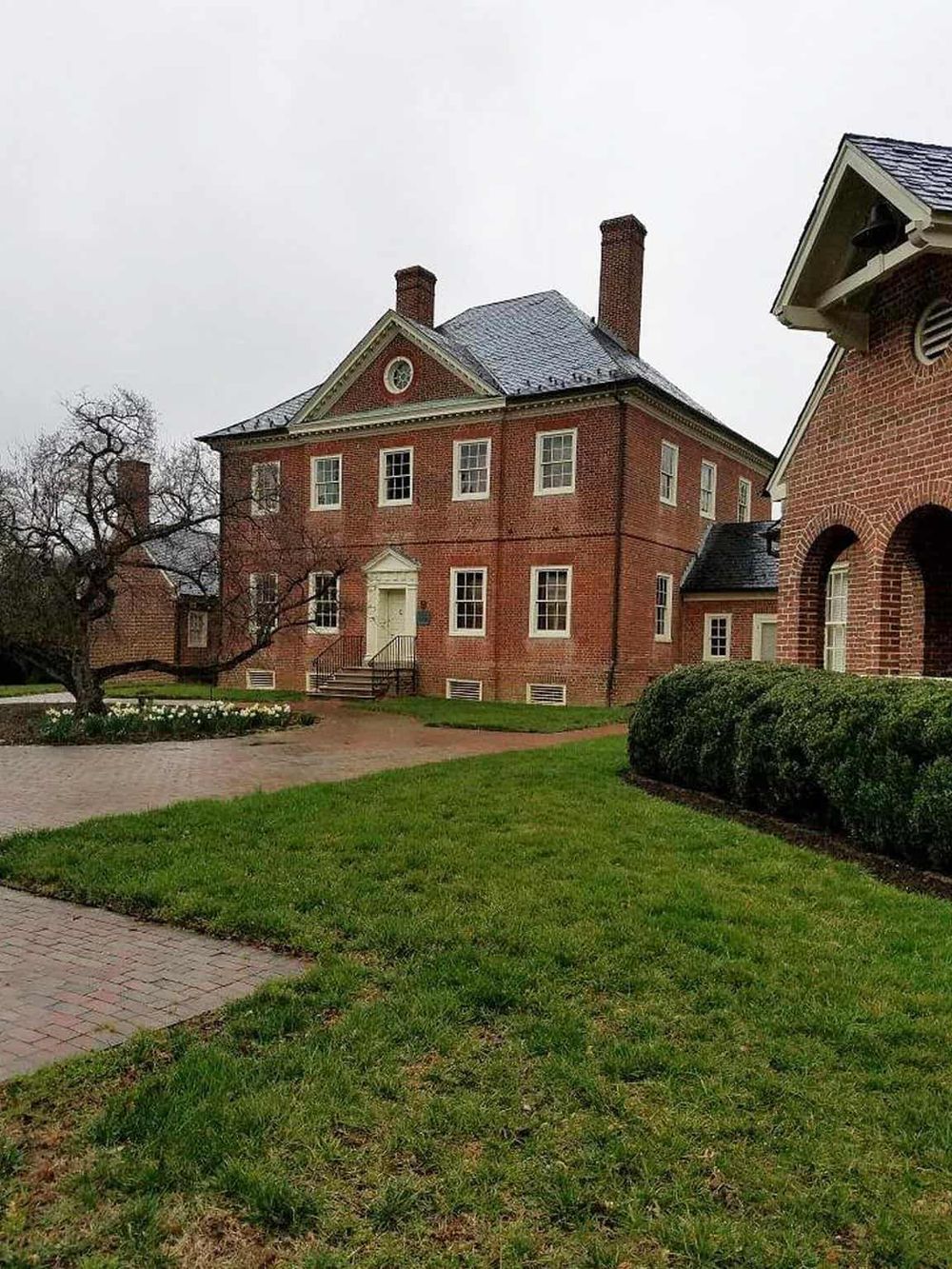 Traditional brick house with lush green lawn and historic architecture, located in a serene neighborhood.