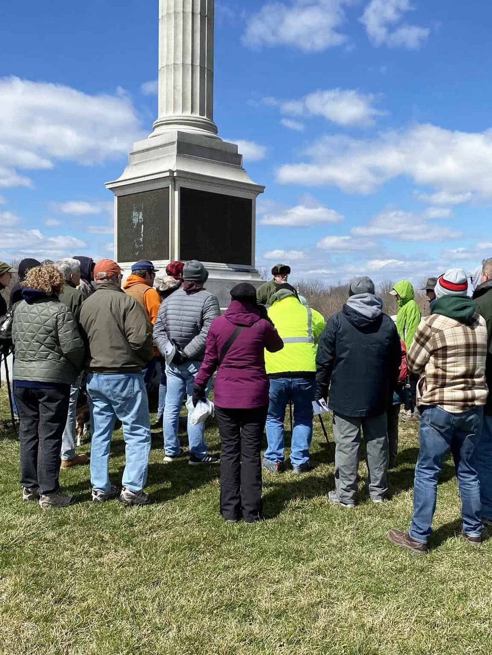 Group of people on a guided tour at outdoor historic monument, exploring local history and heritage.