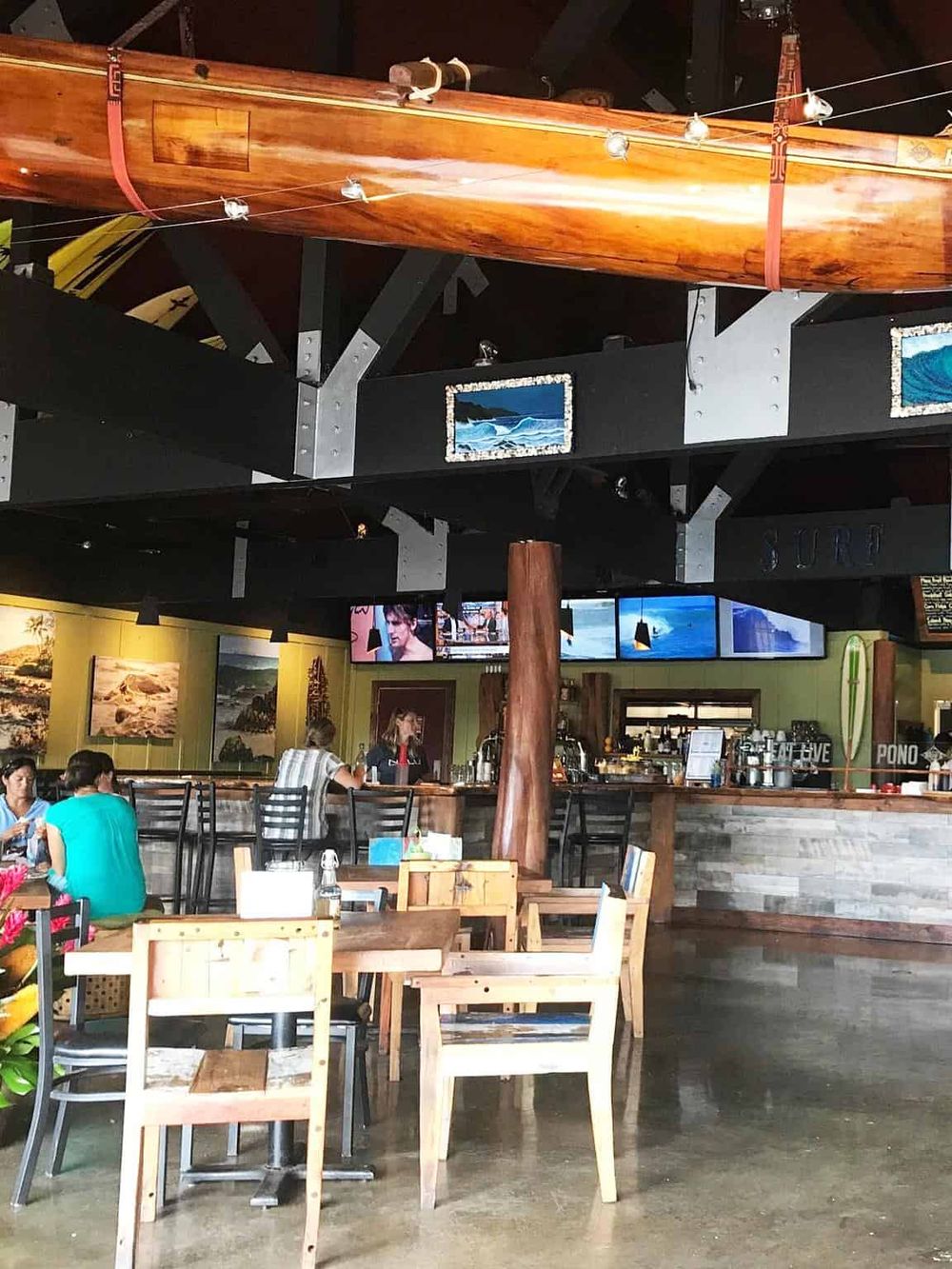 Kayak hanging indoors at Quest for Directions restaurant with dining area, promoting adventure and outdoor activities.