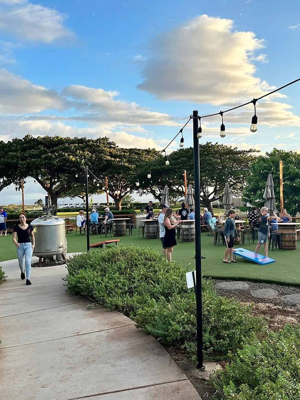 Outdoor dining and socializing area with string lights, trees, and people at QuestForDirections.