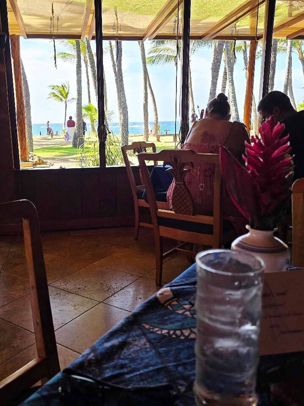 Beachside cafe with ocean view, tropical palm trees, and relaxing atmosphere for travelers.