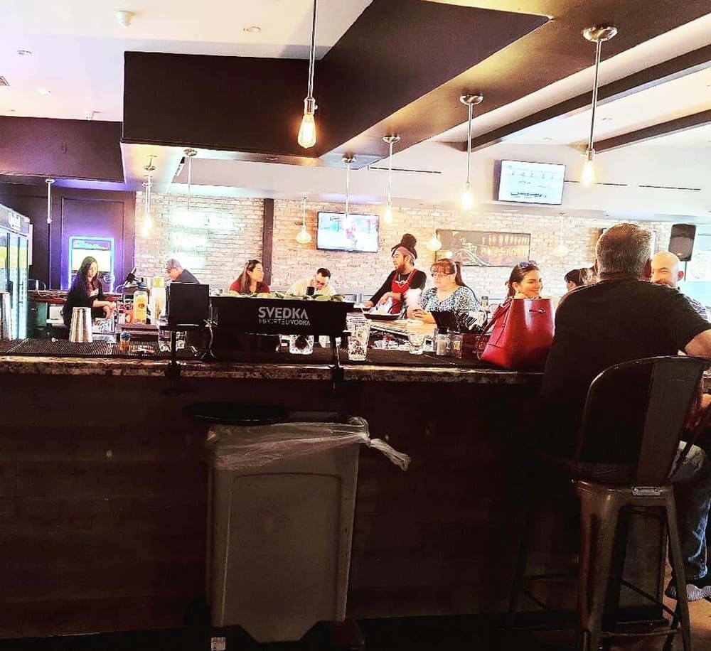 Cozy bar interior with patrons enjoying drinks and socializing in a warm, modern setting.