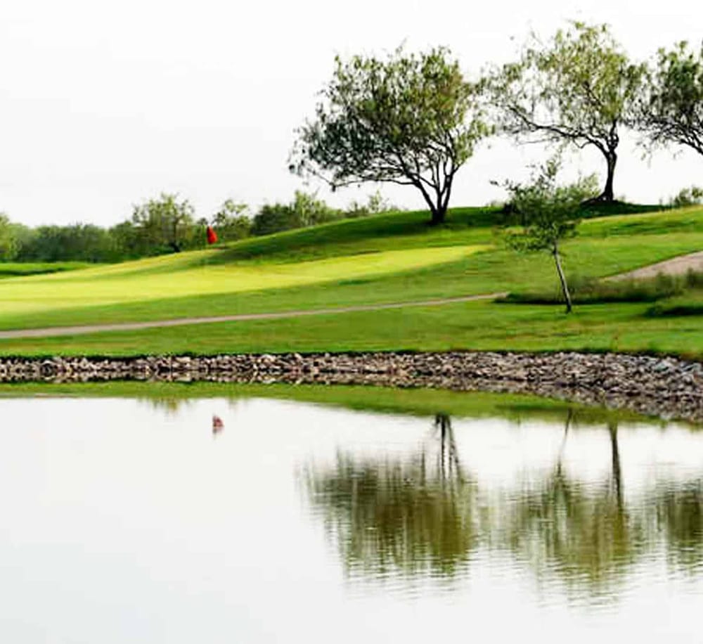 Serene golf course landscape with water features and lush trees, ideal for outdoor recreation and scenic views.
