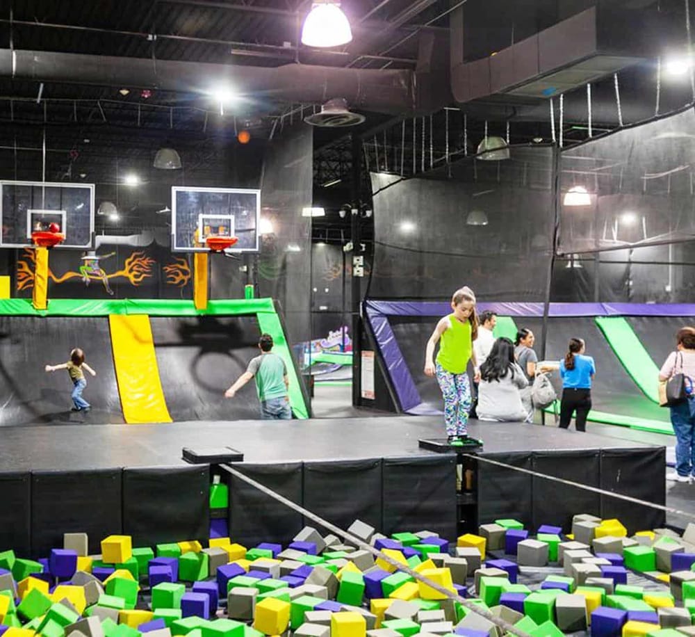 Colorful indoor trampoline park with kids playing and adults supervising, vibrant and fun family activity center.