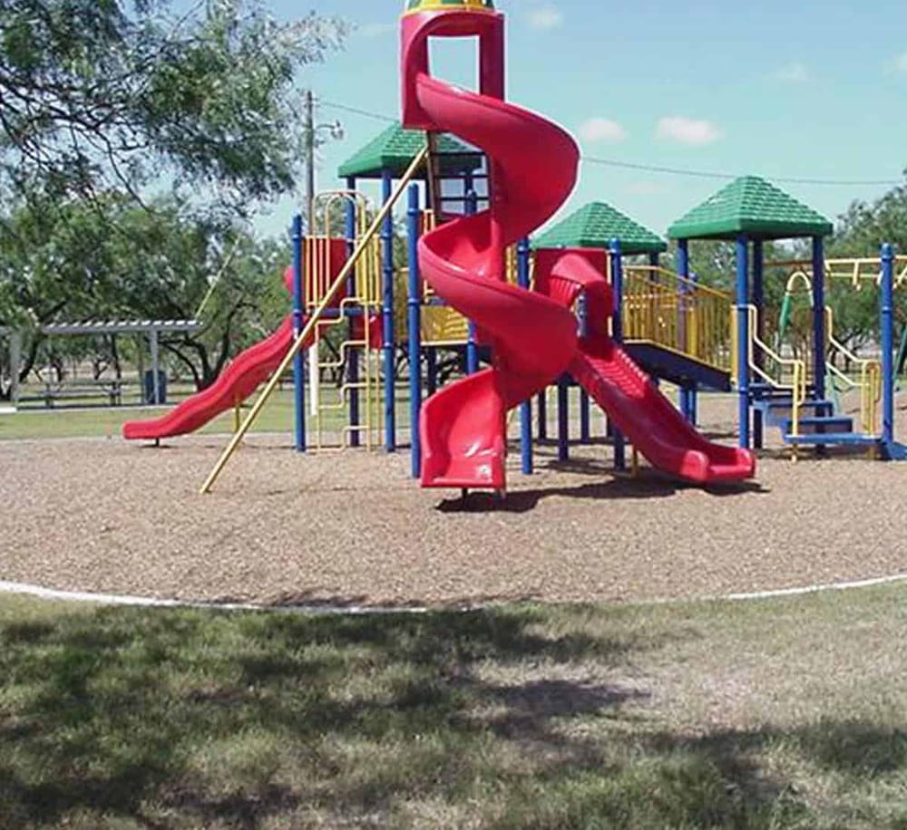 Colorful playground equipment with multiple slides and climbing structures in a park setting.
