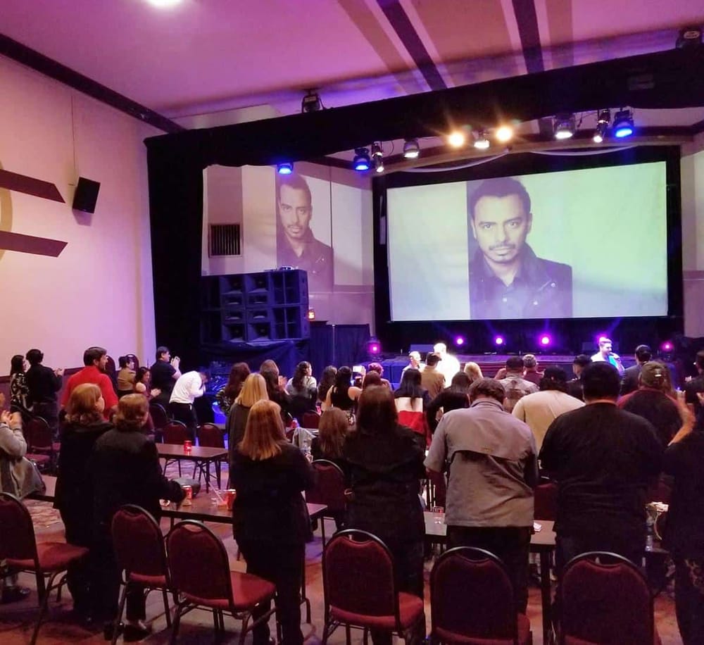 Dynamic event audience watching a speaker on large projection screen at QuestForDirections conference.
