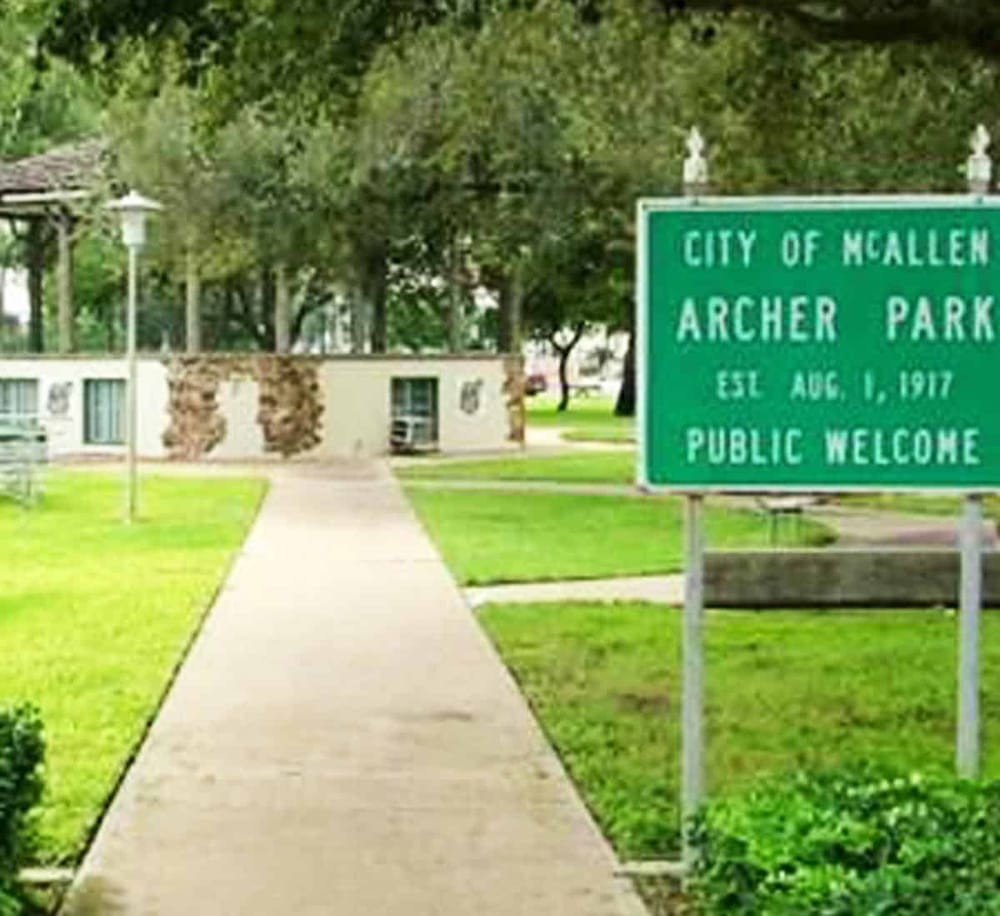 Quiet park entrance at Archer Park, Mallen City, established August 16, 1917, with lush greenery and welcoming atmosphere.