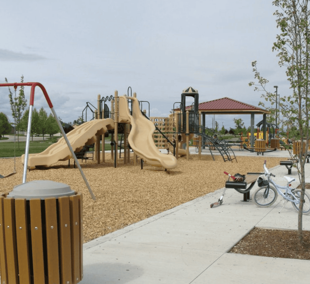 Colorful playground equipment with slides, swings, and seating area in a park setting.