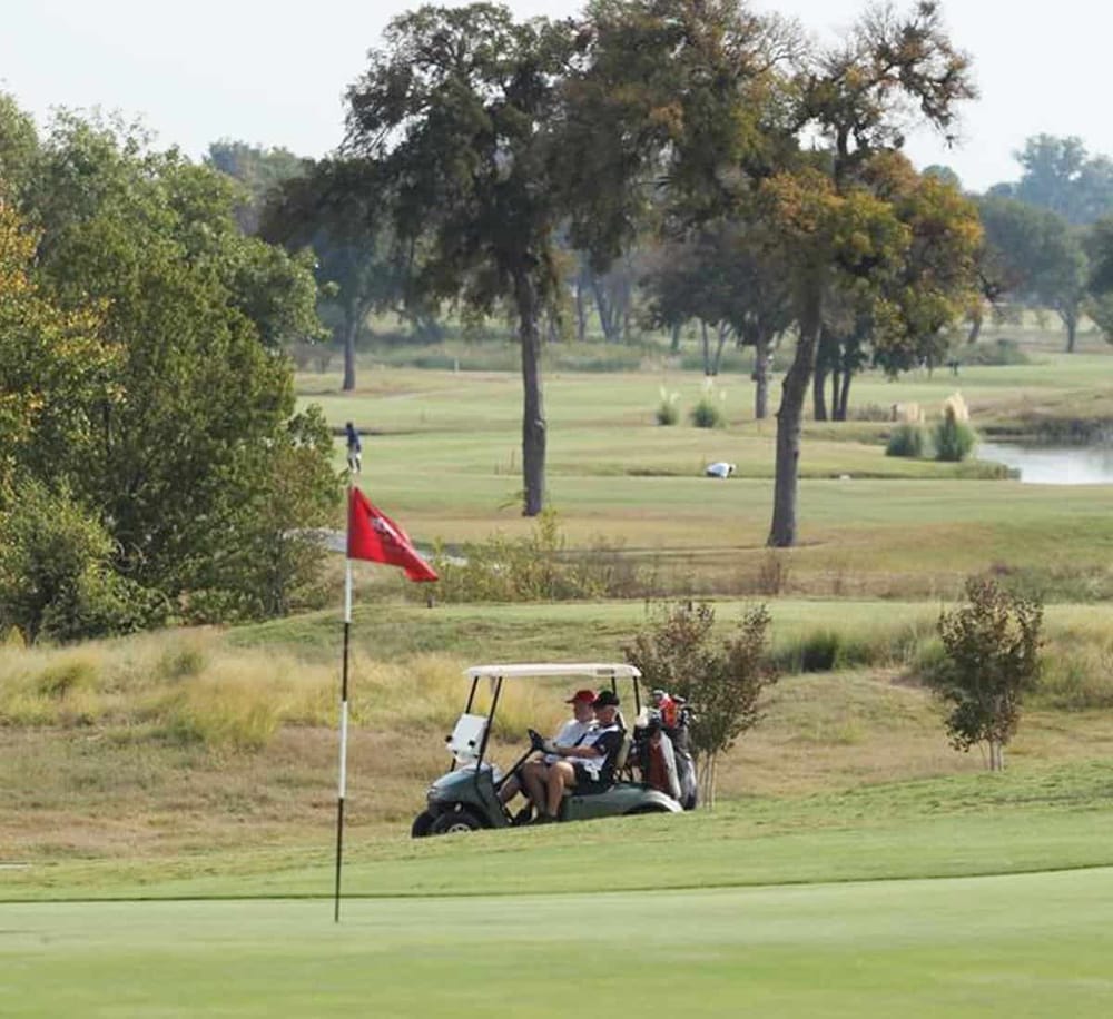 1. Golf cart on a scenic golf course with trees and water features in the background.