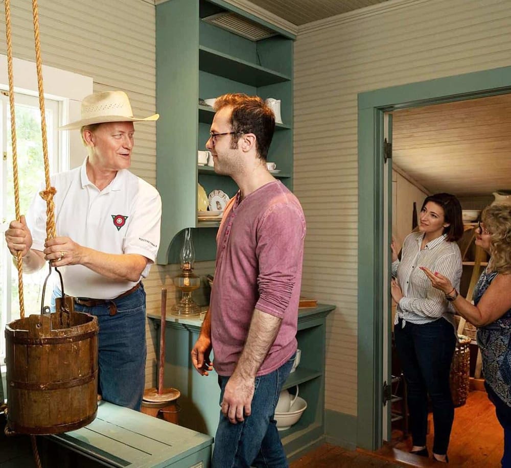 Old-fashioned butter churn demonstration at Heritage Farm. Visitors learn traditional churning methods in a cozy farm setting.