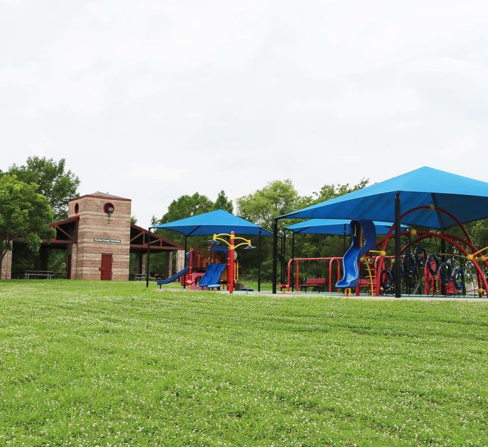 Colorful children’s playground at Valley Creek Park, with slides, swings, and shade covers for outdoor fun.