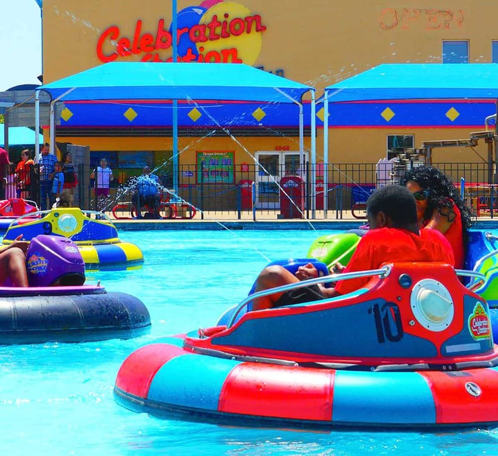 Colorful bumper boats at family amusement park for kids, with water spray feature.