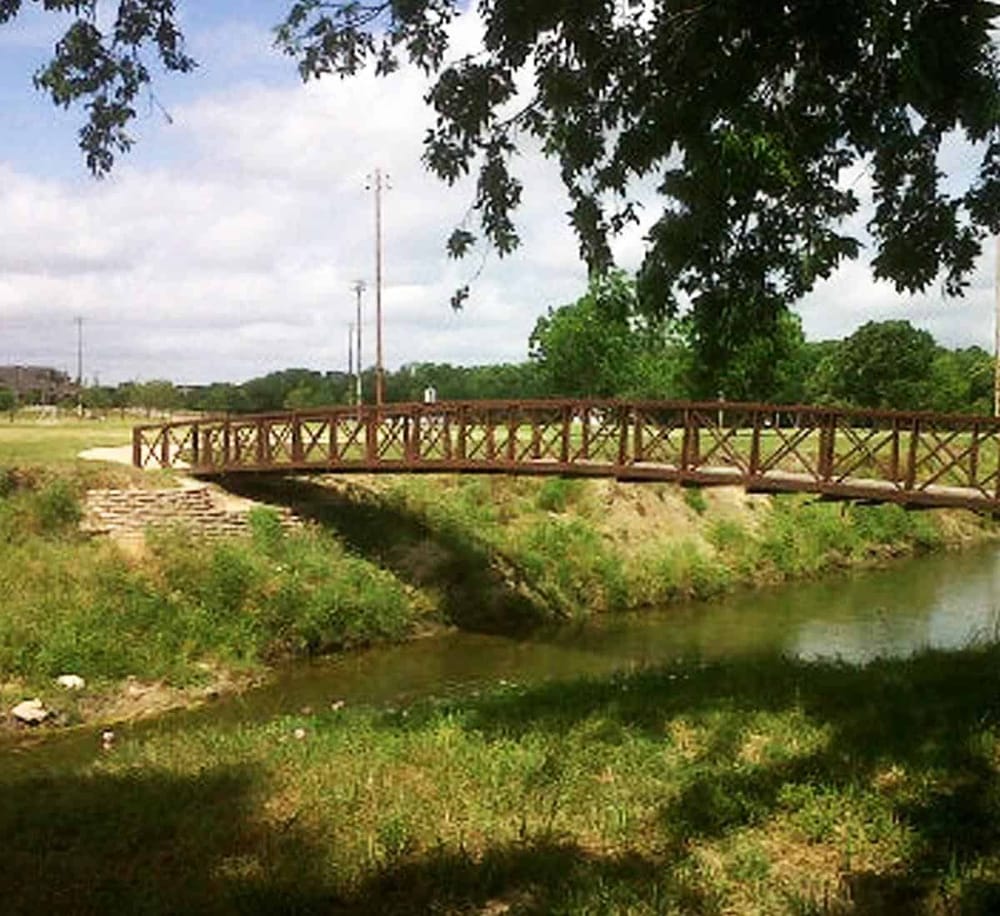 Quiet park bridge over water with trees, ideal for outdoor exploration and nature walks.