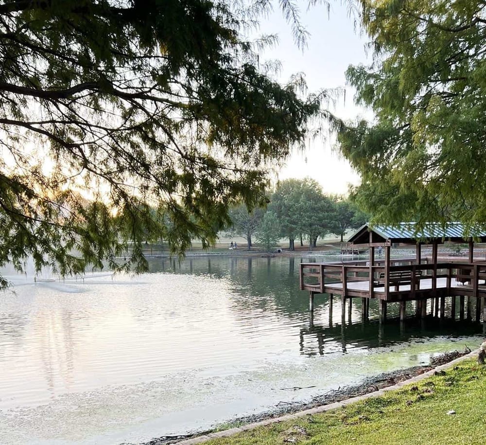 Serene lakeside scene with wooden dock, surrounded by lush trees and peaceful water. Perfect for nature and outdoor recreation.