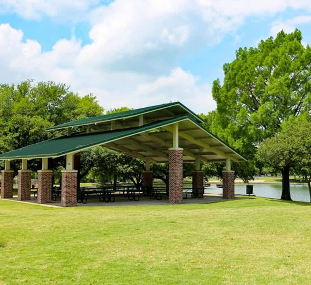Spacious outdoor park pavilion in green surroundings, ideal for gatherings and outdoor events.