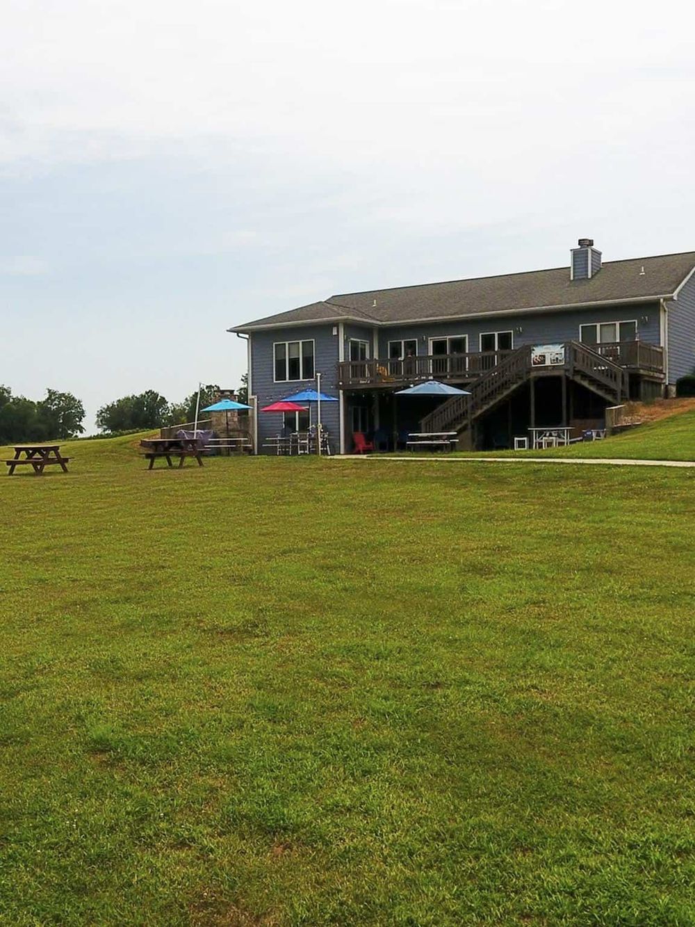 Scenic house with large backyard, outdoor seating, and colorful umbrellas, perfect for outdoor gatherings and relaxation.