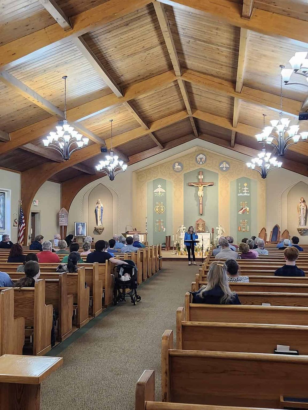 Colorful church interior during service with wooden pews and vaulted ceiling.