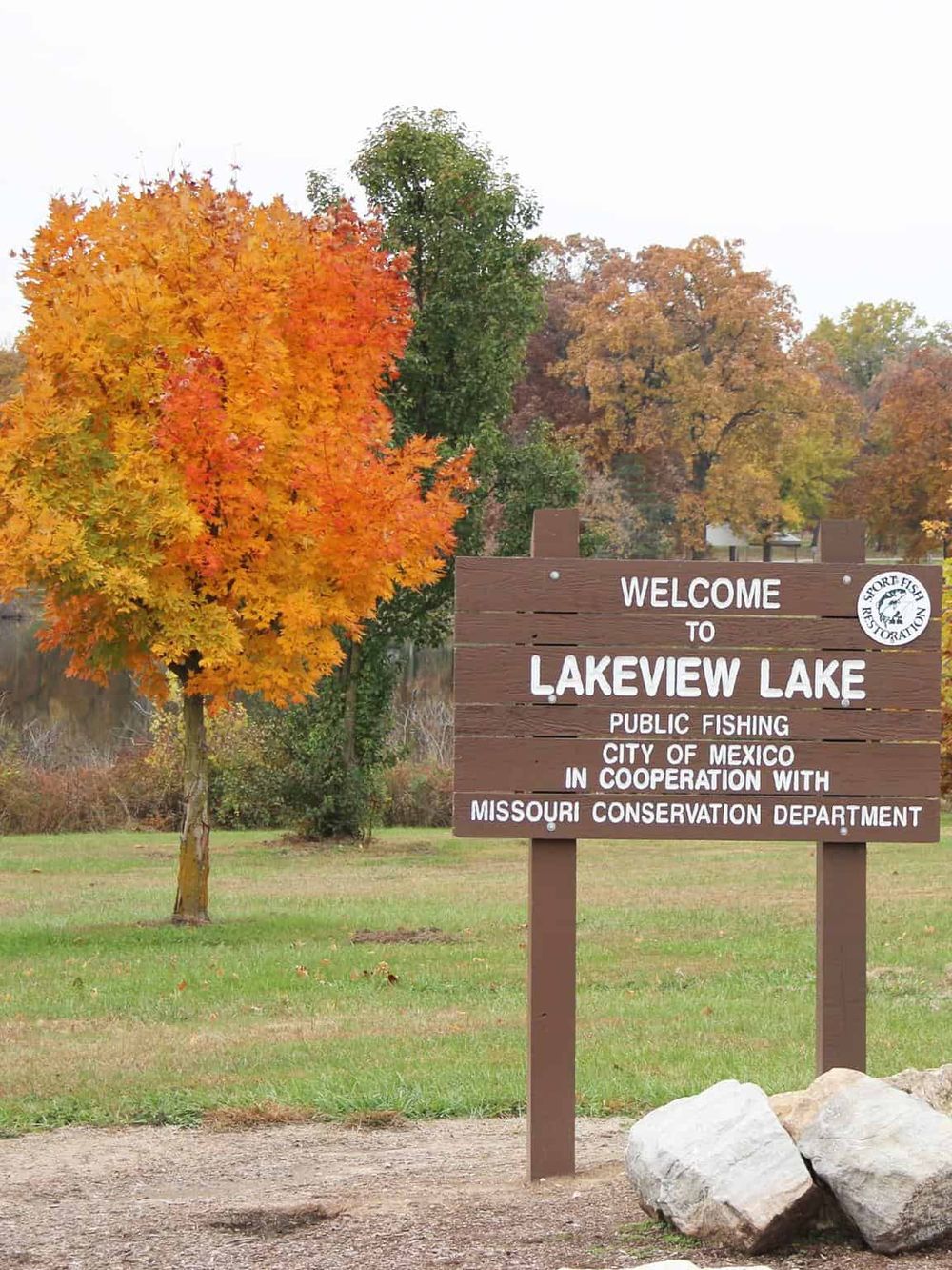 Colorful fall foliage at Lakeview Lake, Missouri, with a welcoming sign for public fishing and conservation efforts.