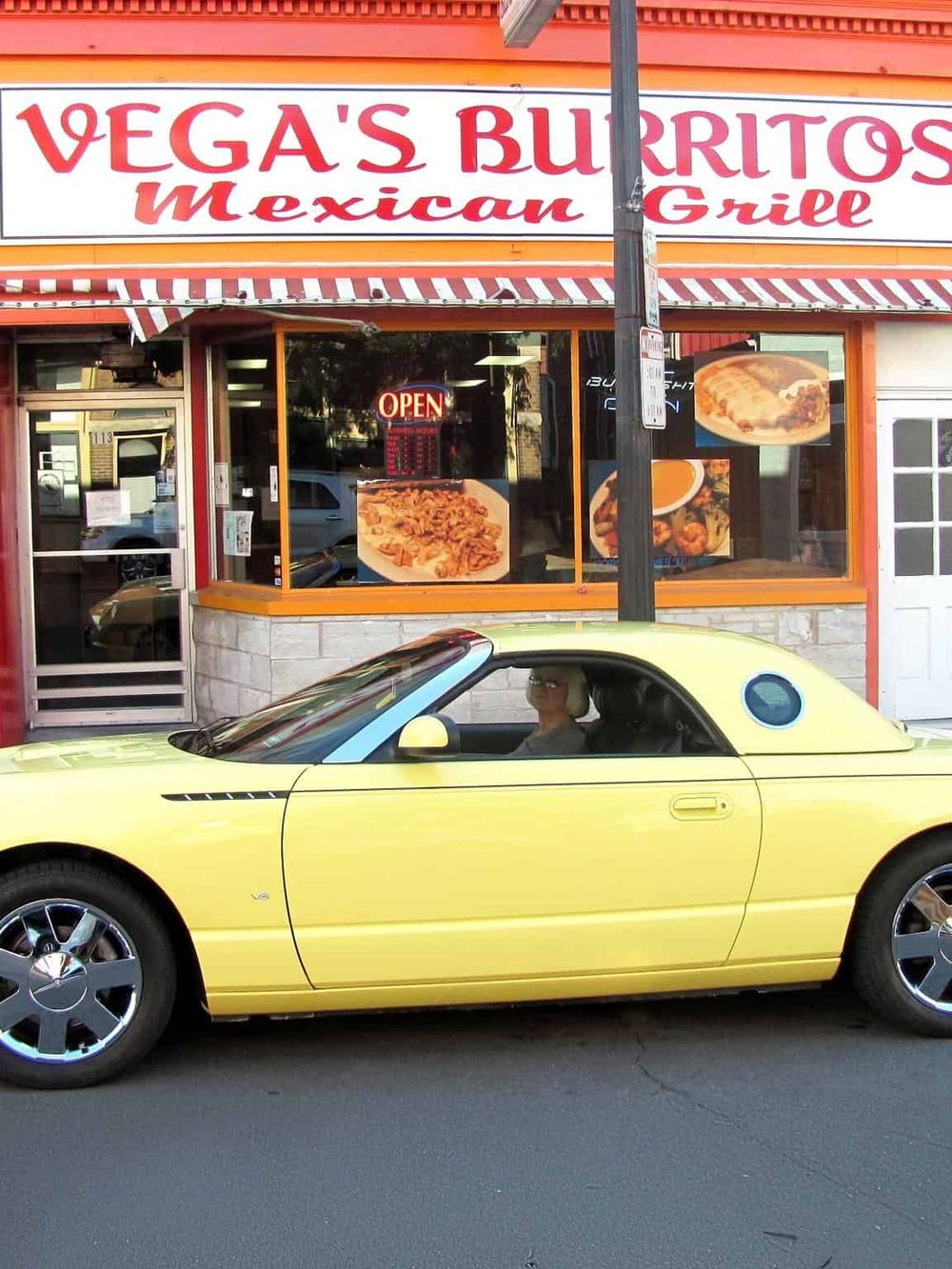Vega's Mexican Grill storefront with bright signage and a yellow convertible car parked outside.