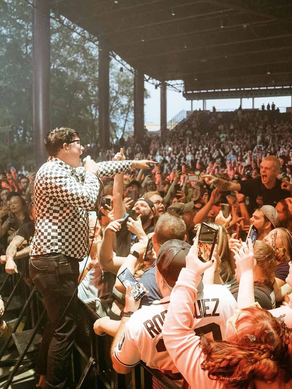 Actual concert with enthusiastic crowd, singer engaging with fans in a large indoor venue.