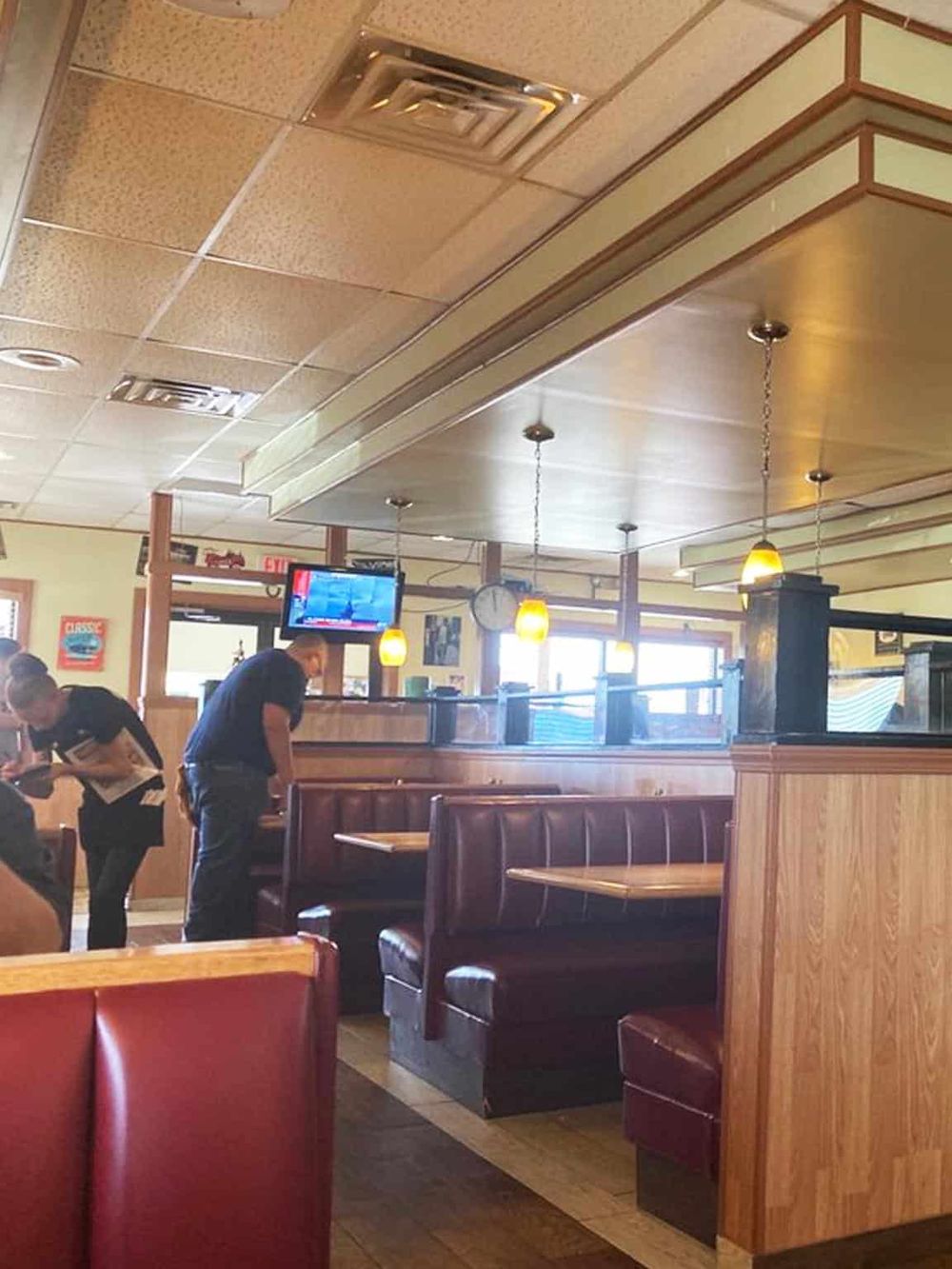 Cozy restaurant interior with booths, staff, and a TV for dining and relaxation.