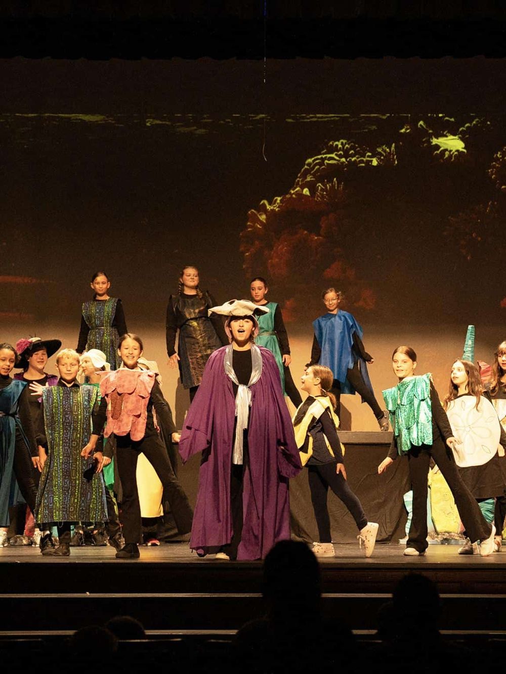 Children performing on stage in theatrical costumes for a school play or musical.