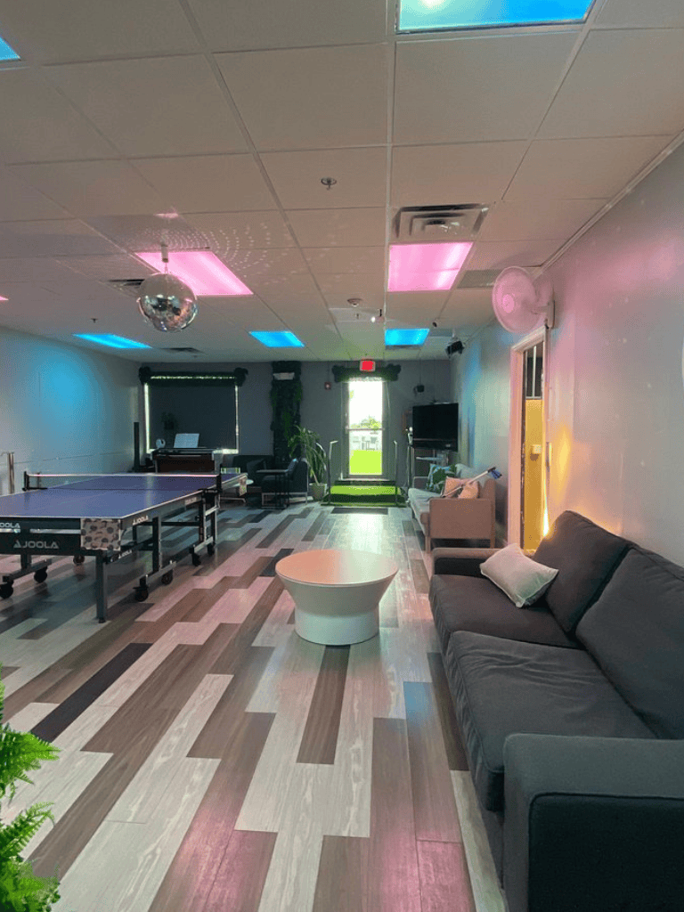 Bright lounge with ping pong table, modern decor, colorful ceiling lights, and a cozy seating area at QuestForDirections.