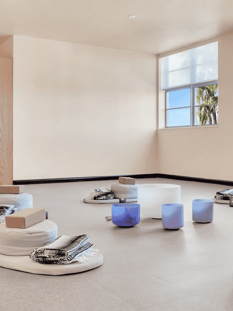 Serene meditation room with low cushions, glowing stools, and natural light for relaxation and mindfulness.