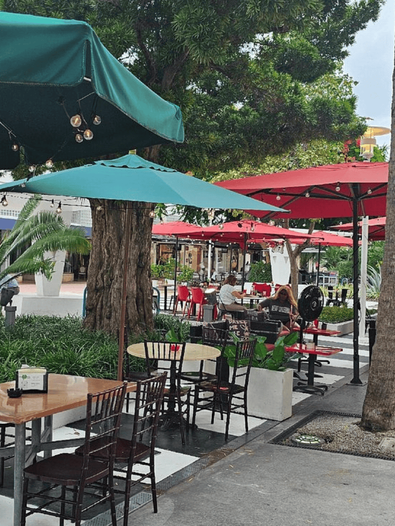 Colorful outdoor cafe dining area with umbrellas, tables, and greenery at QuestForDirections.