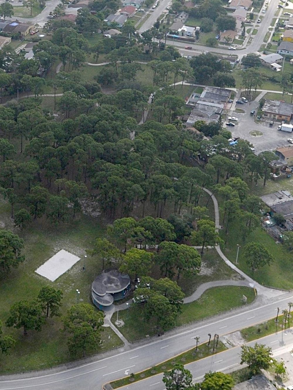 Lush green park with walking trails and pavilion in an urban neighborhood.