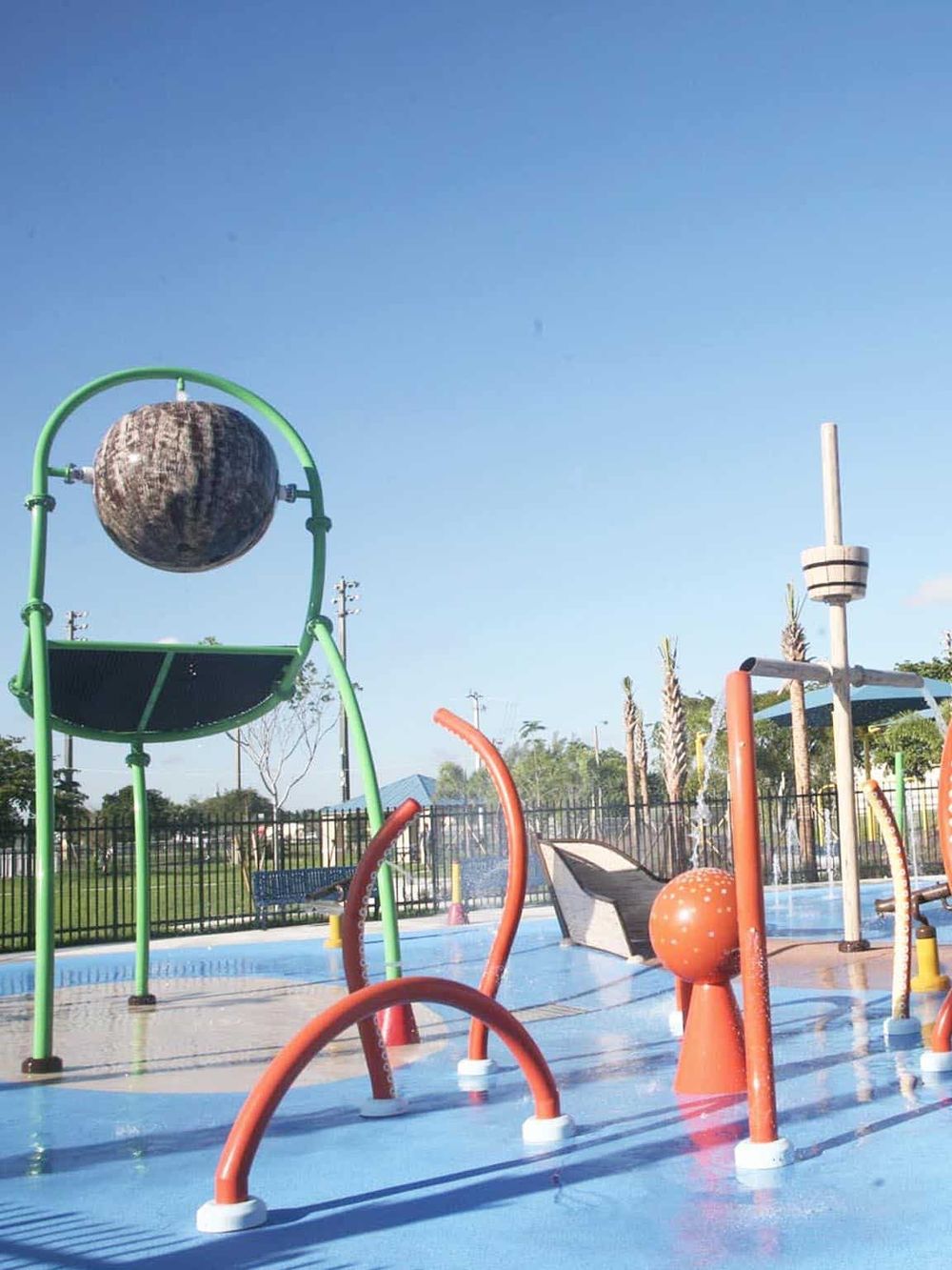 Colorful outdoor splash pad water play area with water sprayers and globe sculpture, ideal for family fun and children's entertainment.