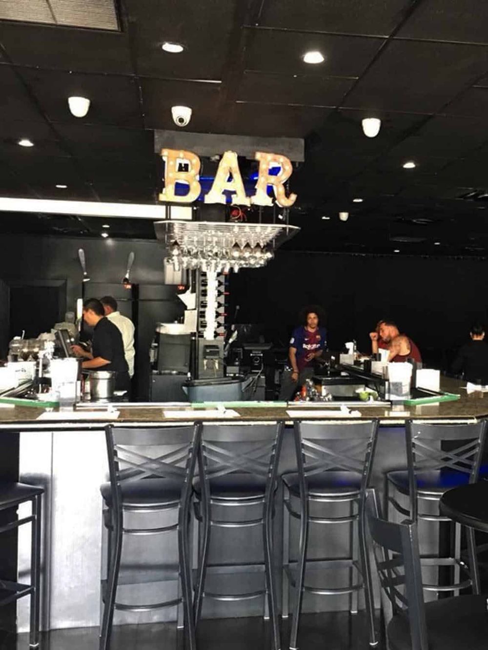 Modern bar counter at Quest For Directions with bartender preparing drinks.
