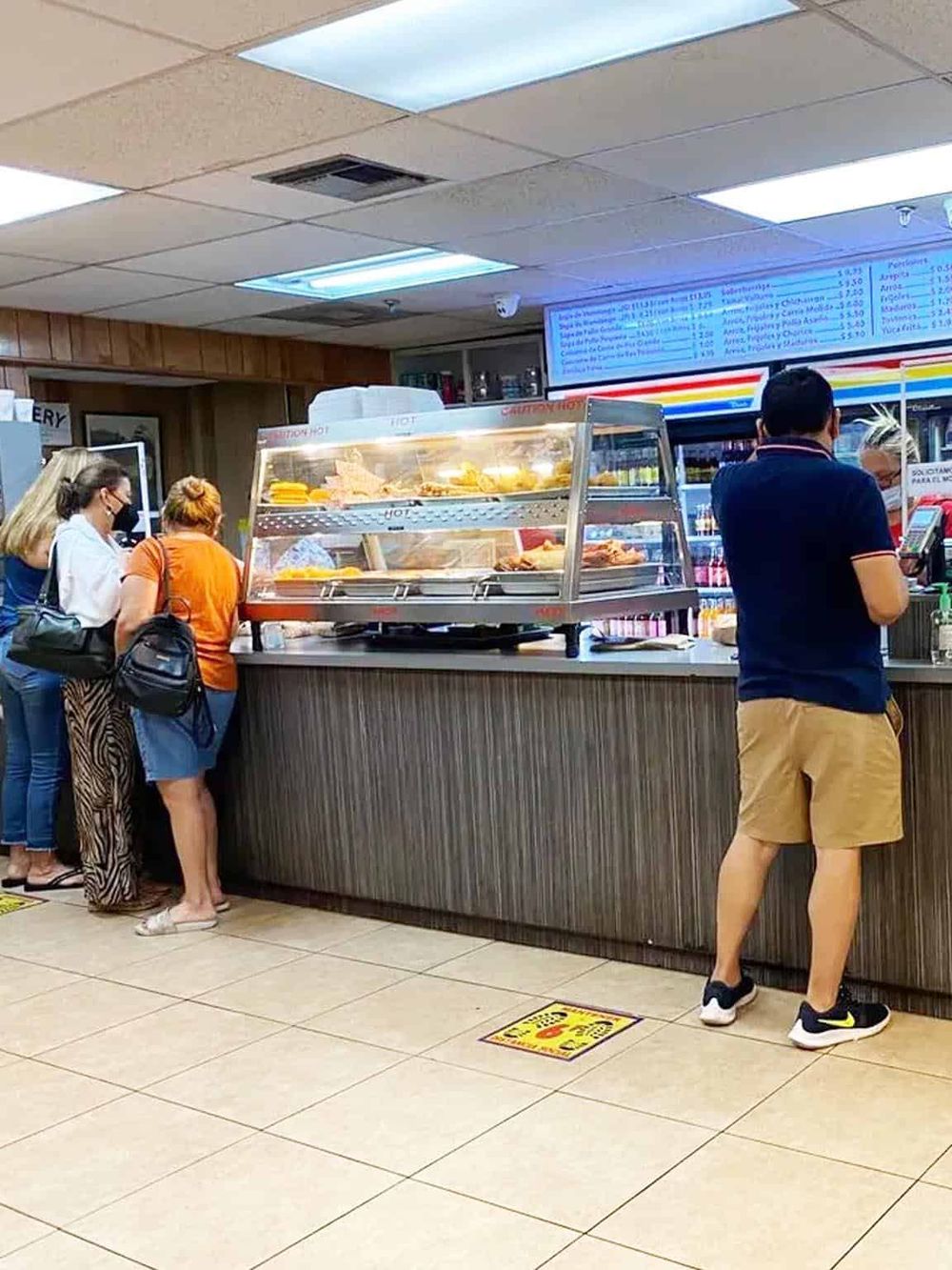 Freshly baked food at a quick-service restaurant counter, customers waiting for order, casual dining environment.