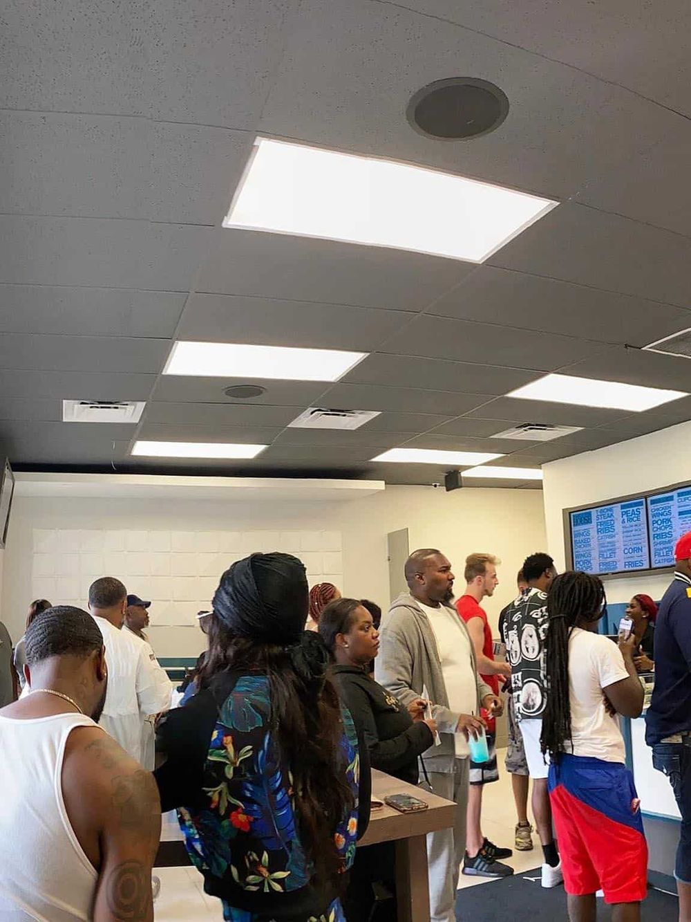 People waiting in line at QuestForDirections food service counter, diverse crowd, vibrant community hub, modern interior design.