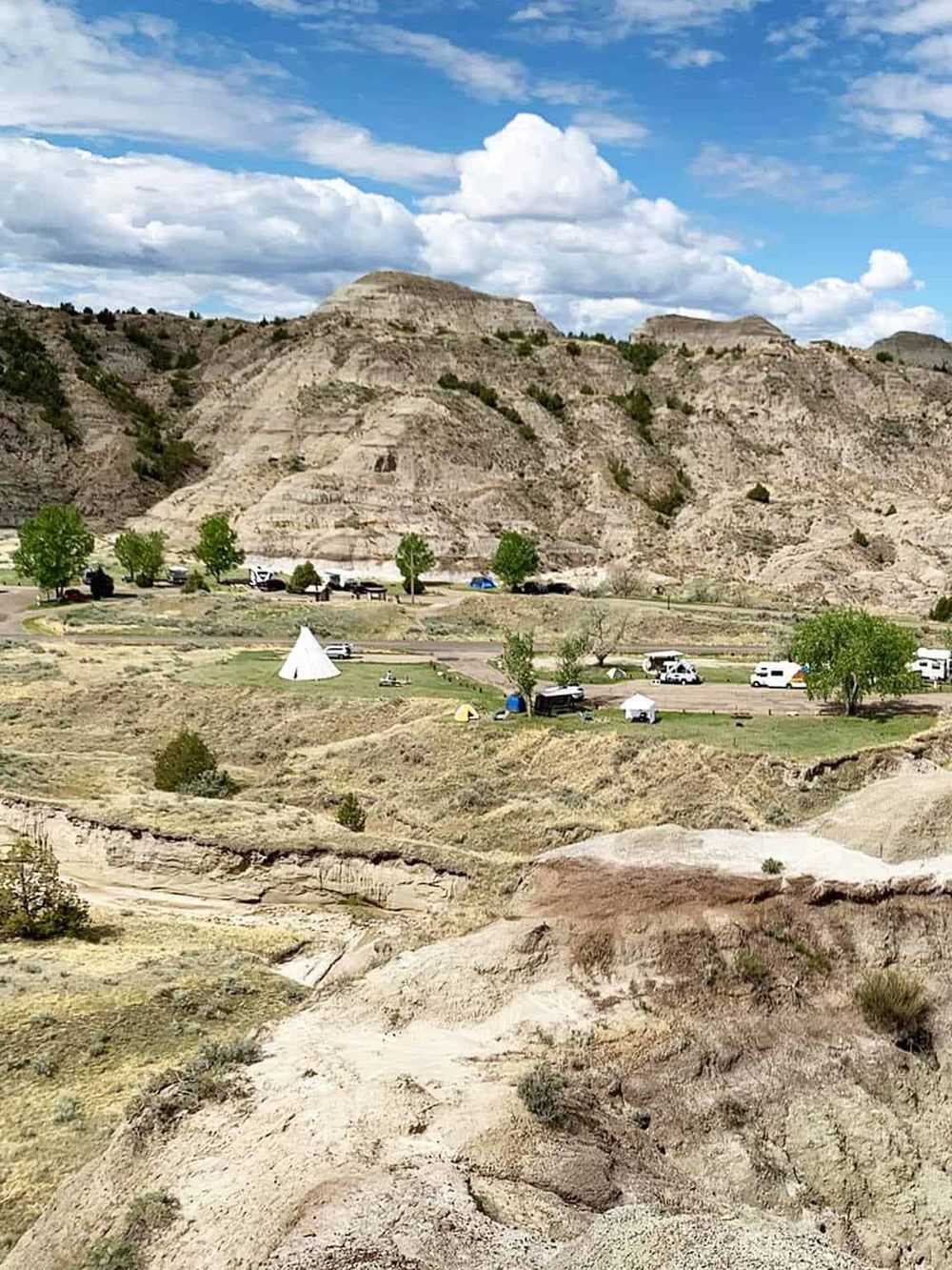 Rugged canyon landscape with camping, trees, and mountain backdrop, scenic outdoor adventure destination.