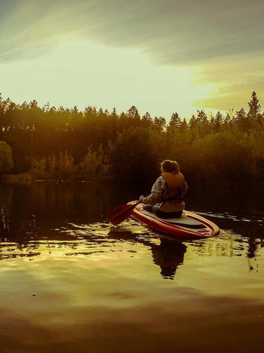 Peaceful kayaking on a river during sunset, surrounded by lush forest.