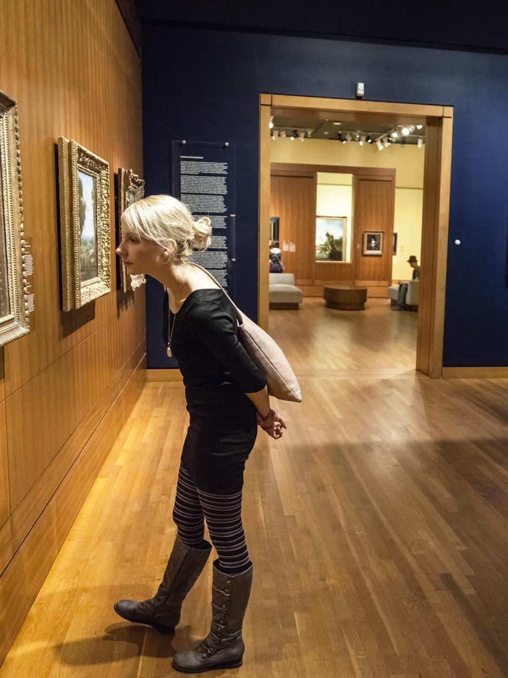 Elegant woman closely observing artwork in a museum gallery.